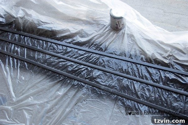 Polystyrene moulding pieces laid out on a drop cloth in the garage after being spray painted on both sides for the industrial shower door grid.