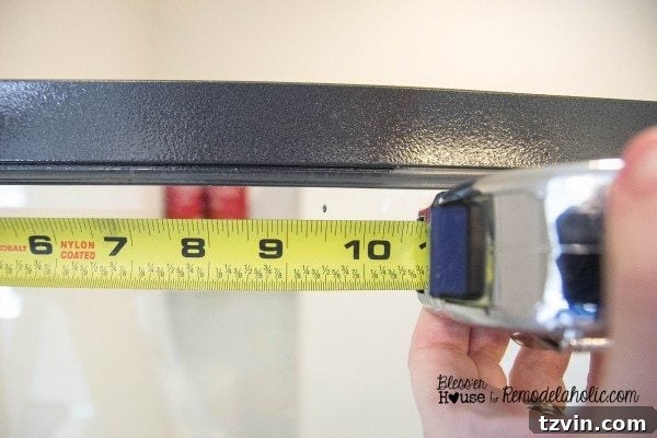 Using a black permanent marker and tape measure to mark the precise placement of vertical moulding strips on the shower glass.