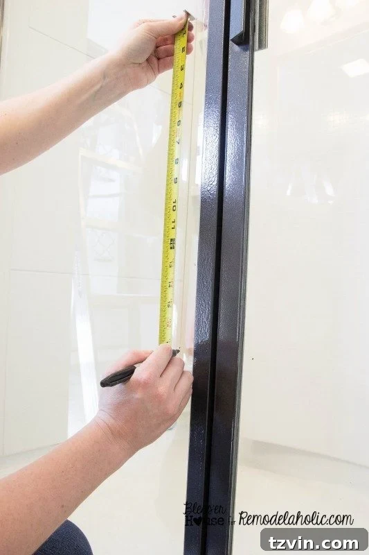 Marking horizontal grid lines on the shower glass after dividing the total height by four for even pane spacing.