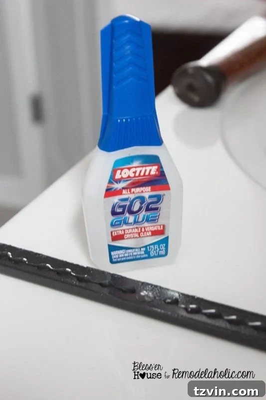 Applying Loctite GO2 Glue to the backside of a painted polystyrene moulding strip, preparing it for adhesion to the glass.