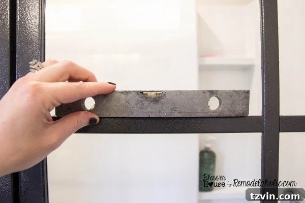Attaching horizontal polystyrene moulding strips to the shower glass, using a small level to ensure perfect alignment.
