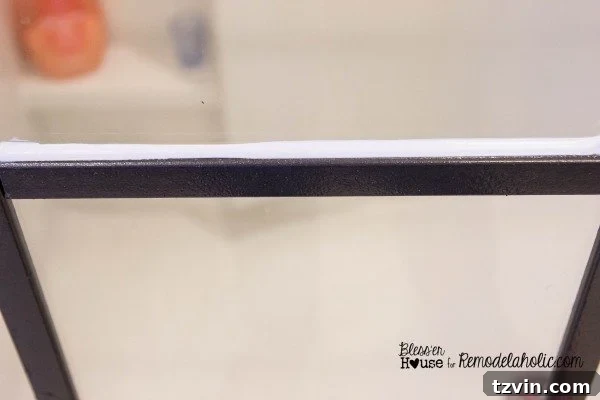 Using a caulk gun to apply a continuous bead of clear latex caulk along the side of a moulding strip.