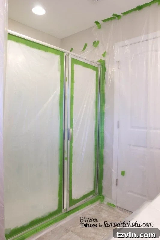 Carefully taping off the shower enclosure and surrounding bathroom surfaces with plastic drop cloths and painter's tape for spray painting.