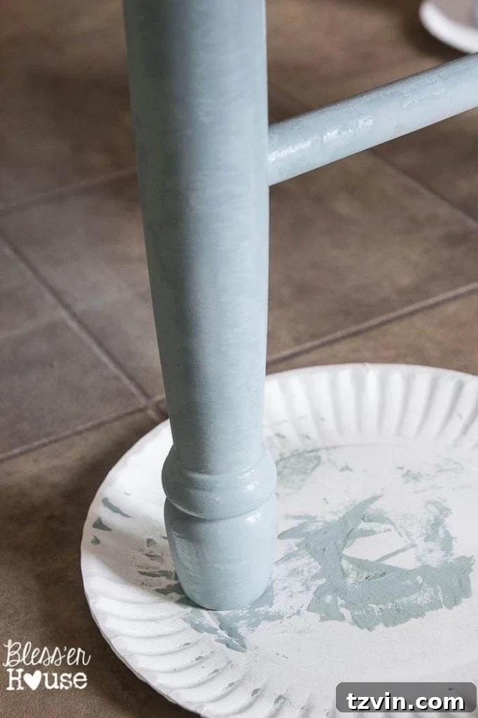 First coat of duck egg blue chalk paint on a dining chair, showing visible brush strokes and streaks which are typical for the initial application.