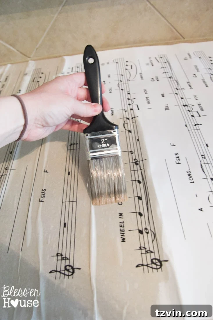 DIY Giant Sheet Music Wall Art 18 Applying brewed black tea to the engineer print with a paintbrush.