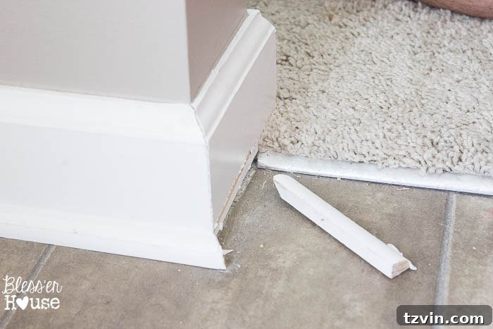 Removing a section of quarter round molding, showcasing the clean separation from the baseboard and floor.