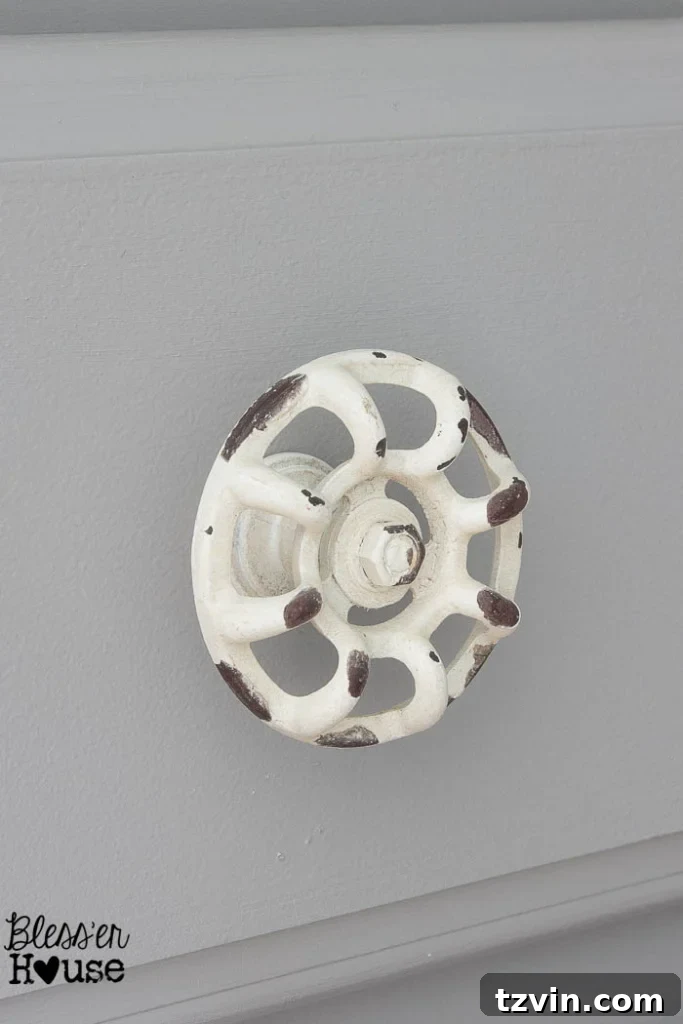 Close-up of a stylish, unique spigot-looking cabinet knob on a crisp white painted cabinet door