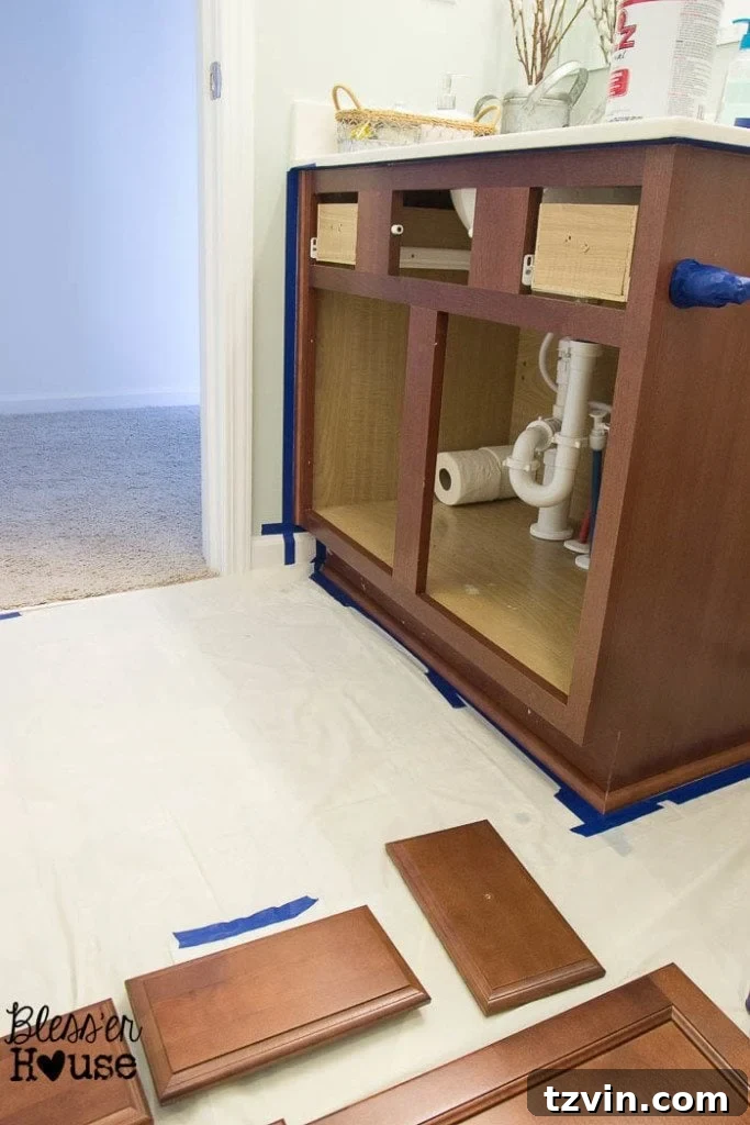Applying painter's tape meticulously around a cabinet box to protect surrounding areas during painting