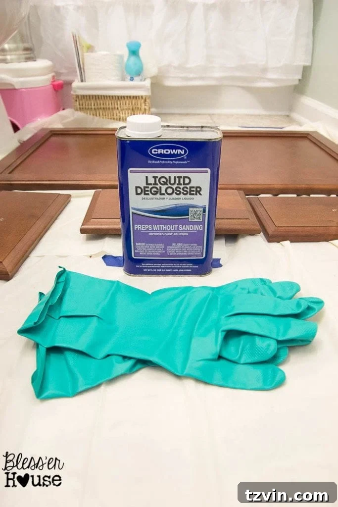 Cleaning cabinet surfaces with liquid deglosser while wearing protective chemical-resistant gloves