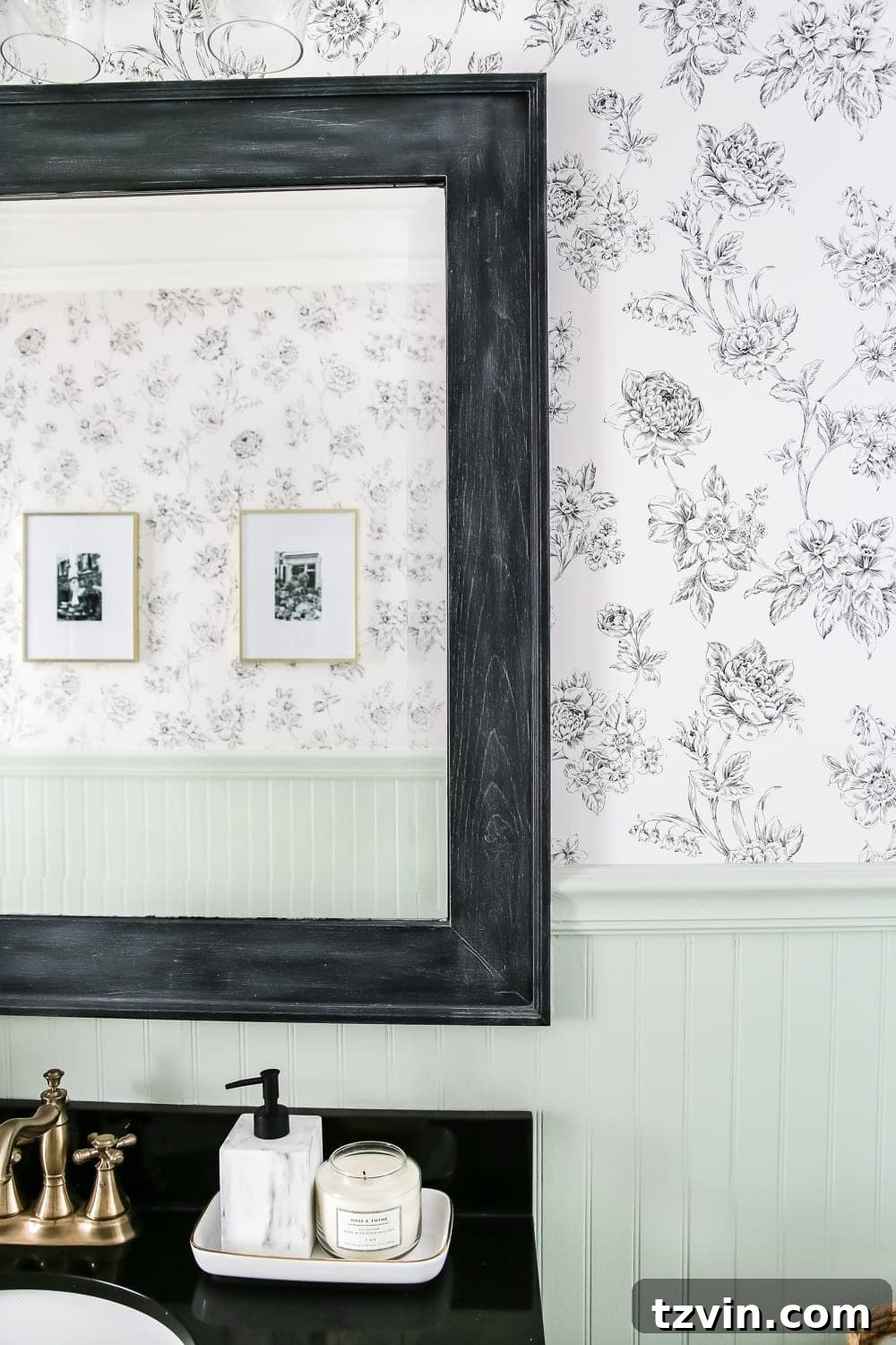 black dry brushed bathroom mirror frame in a powder room with black and white floral wallpaper