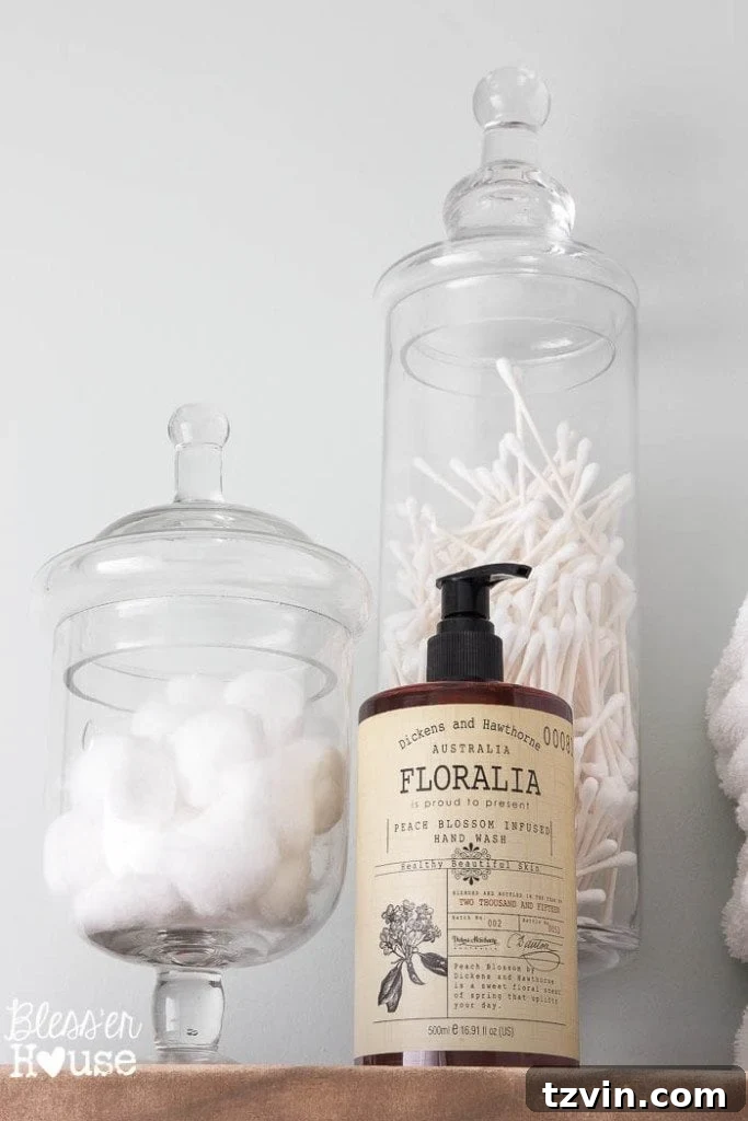 Elegant apothecary jars on shelves, used for both stylish storage and child-proofing, a smart addition to the modern farmhouse bathroom.