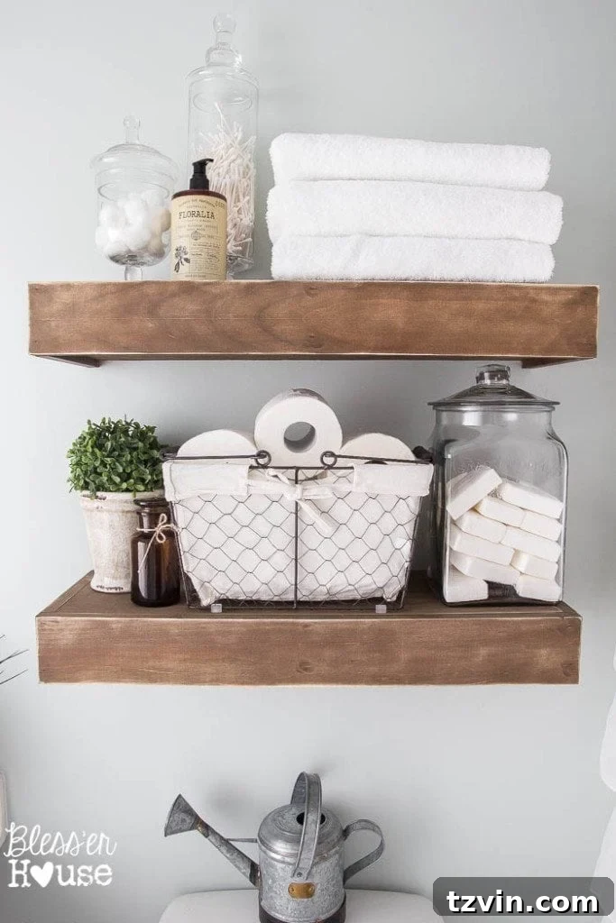 Chunky DIY floating shelves in the modern farmhouse bathroom, stained and distressed, holding guest amenities and charming decor.