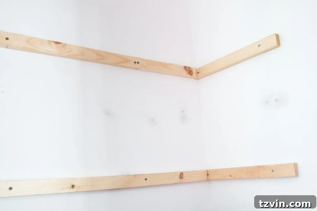 Installing the back 1x2 furring strip to connect the side supports, creating a complete frame for a DIY closet shelf. This adds stability to the shelving unit.
