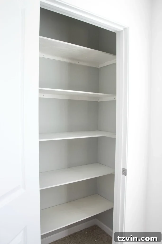 Newly painted white DIY closet shelves and gray walls, showcasing the fresh and organized look after the installation and finishing touches. A perfect craft closet storage solution.