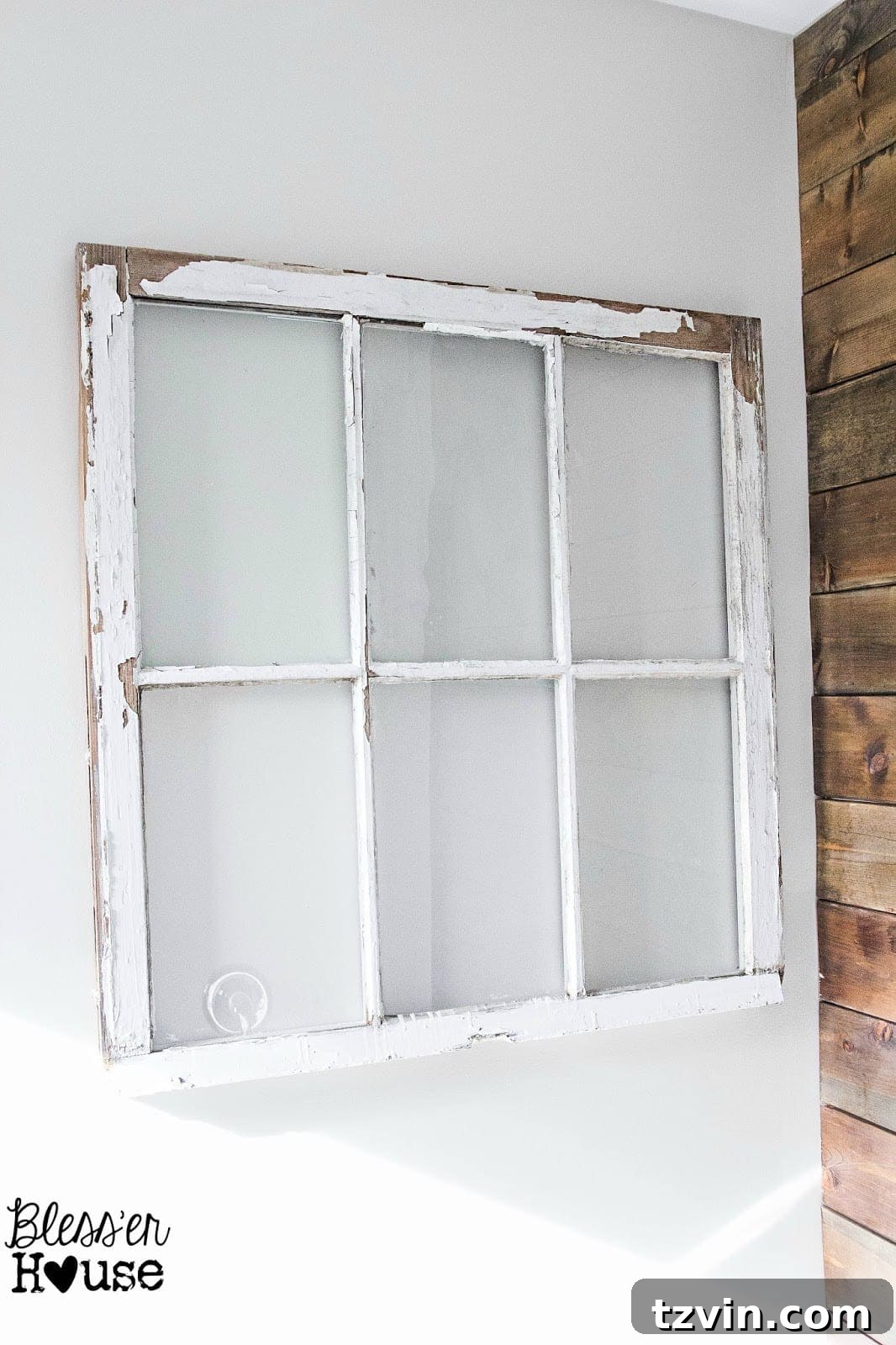 An upcycled vintage window frame, now serving as wall decor, hanging above a bathtub in a master bathroom, showcasing its new purpose.