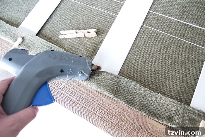 Applying hot glue and pressing fabric onto a blind slat, secured with clothespins for DIY Roman shades