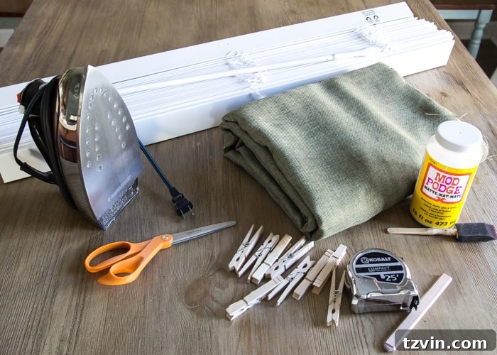 DIY Roman Shades supplies including fabric, blinds, scissors, hot glue gun, and other tools