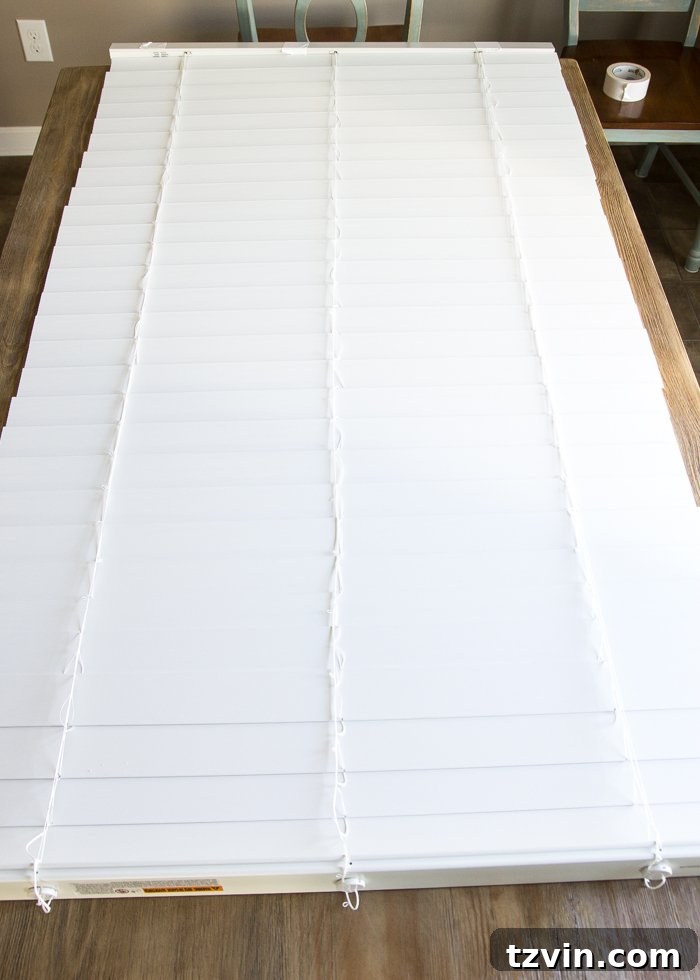 Blinds laid face down on a work table, secured with duct tape for DIY Roman shades