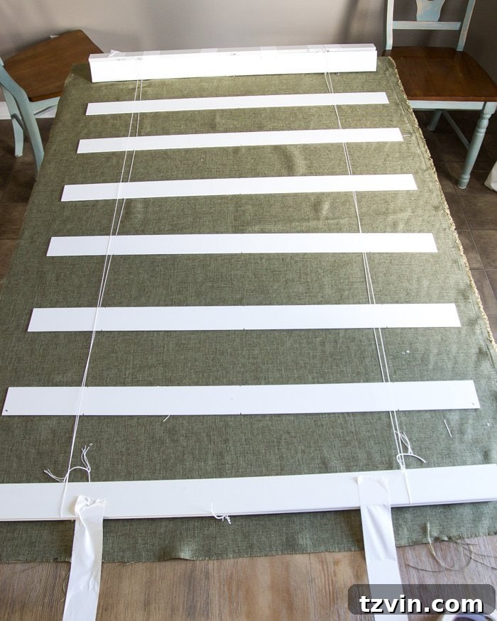 Fabric laid beneath the blind mechanism with slats, ready for measurement and cutting for Roman shades