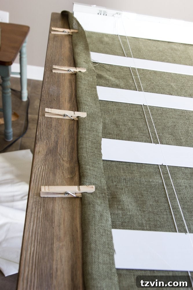 Fabric edges folded over and secured with clothespins, preparing for hemming on DIY Roman shades