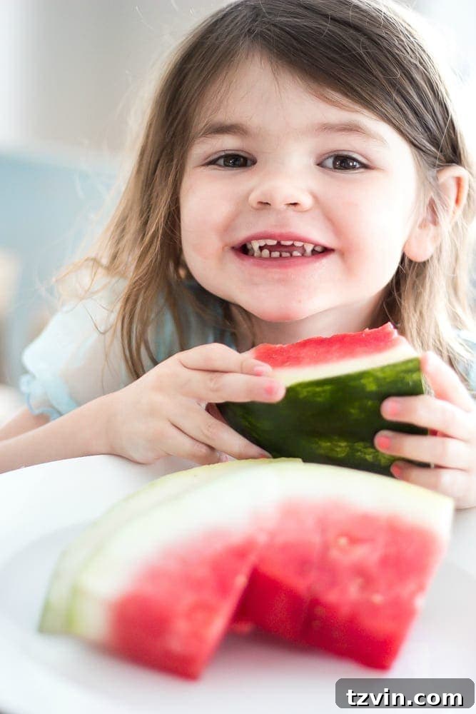 Elevate Your Kitchen: Pro Strategies for Cabinet Painting 23 A child happily eating watermelon slices in the bright, newly painted kitchen, showcasing real life in the beautiful, transformed space.