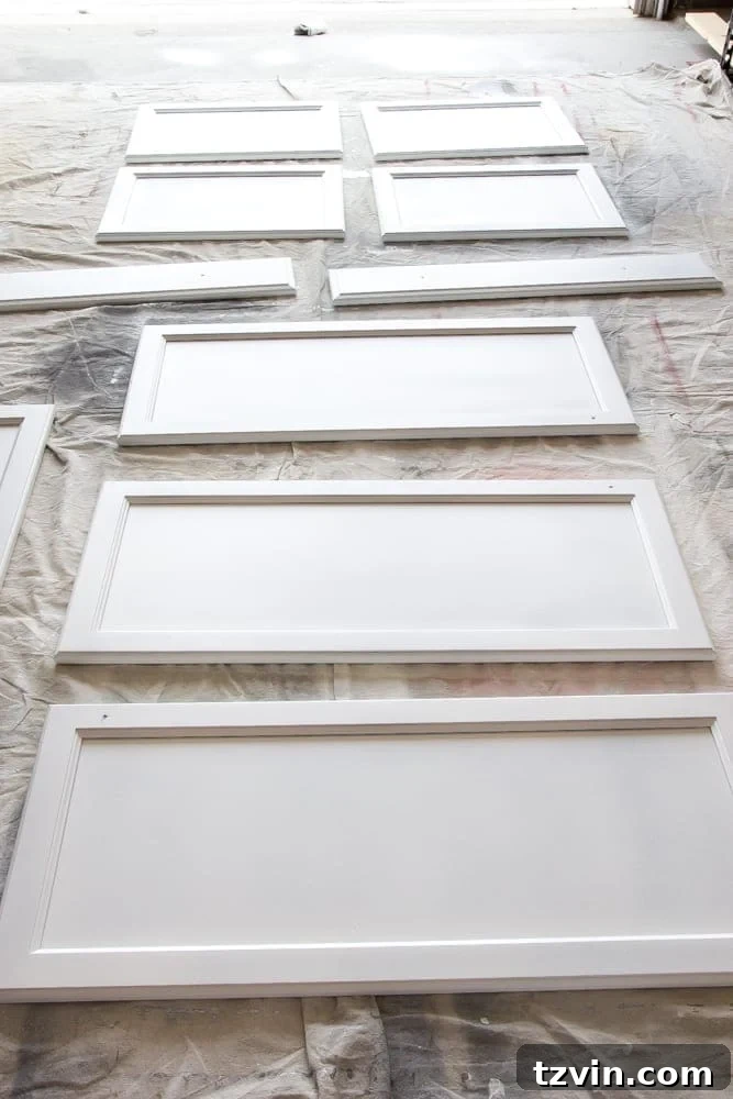Elevate Your Kitchen: Pro Strategies for Cabinet Painting 10 A person applying the final coat of white paint to a kitchen cabinet door front with a sprayer, demonstrating the technique for a smooth, high-quality finish.
