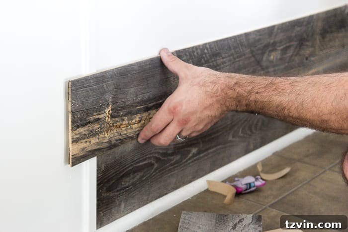 Applying Stikwood planks to kitchen bar, peeling off adhesive backing.
