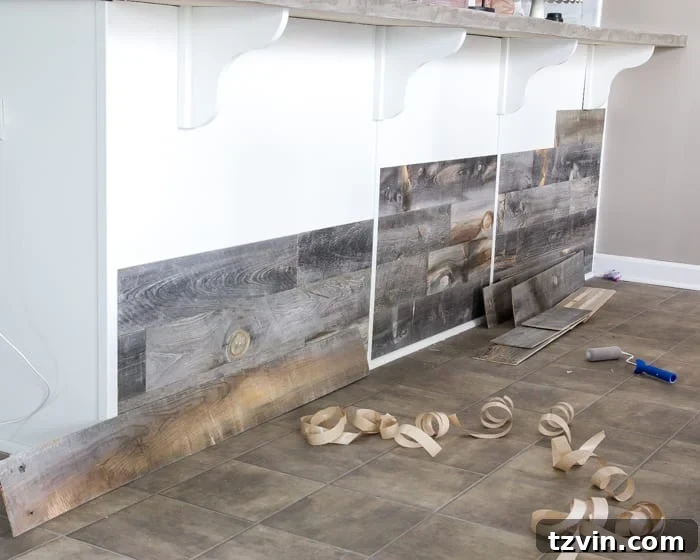 Using a roller to ensure Stikwood planks are firmly adhered to the kitchen bar.