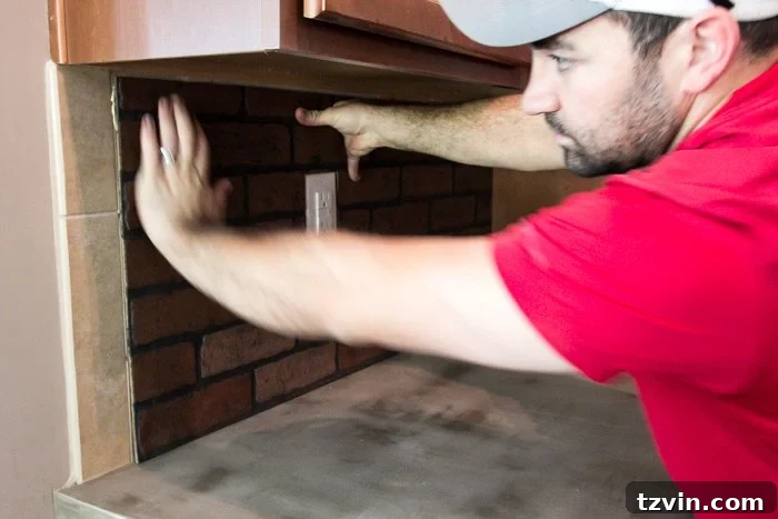 Attaching faux brick paneling over existing tile to create a seamless white brick backsplash