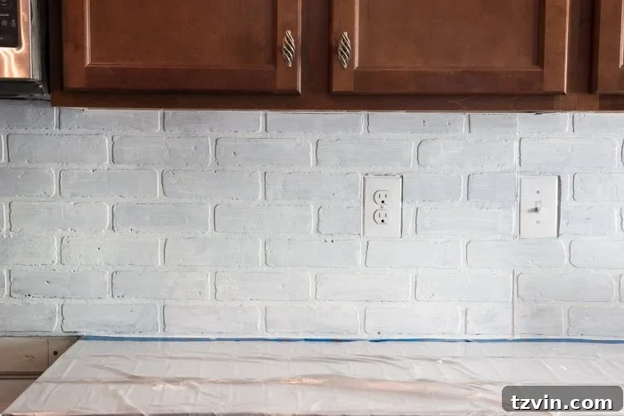 Applying the second coat of whitewash for an even and charming faux brick backsplash