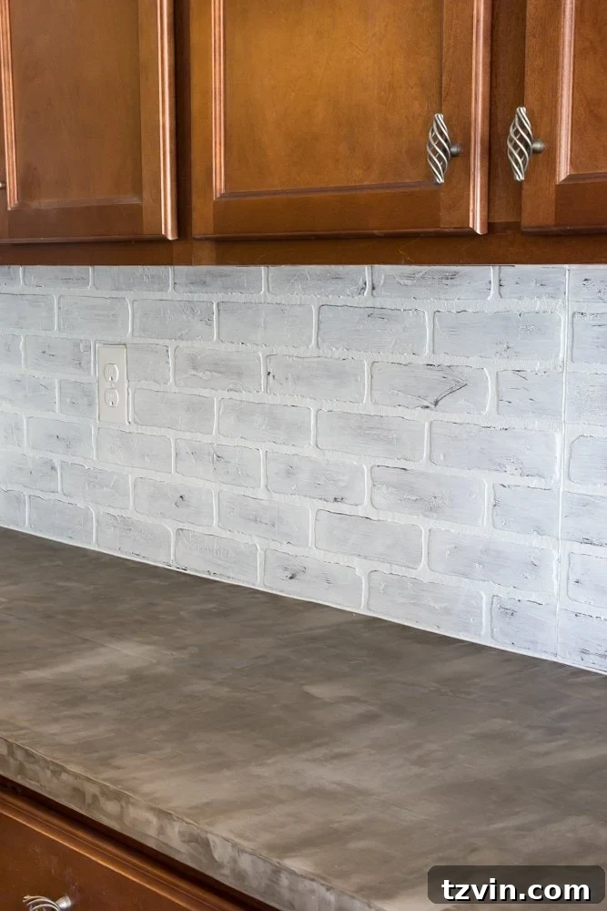 Freshly installed whitewashed faux brick backsplash complementing new concrete countertops