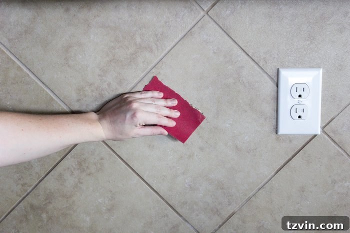 Sanding a tile backsplash to create grip for the faux brick panel adhesive