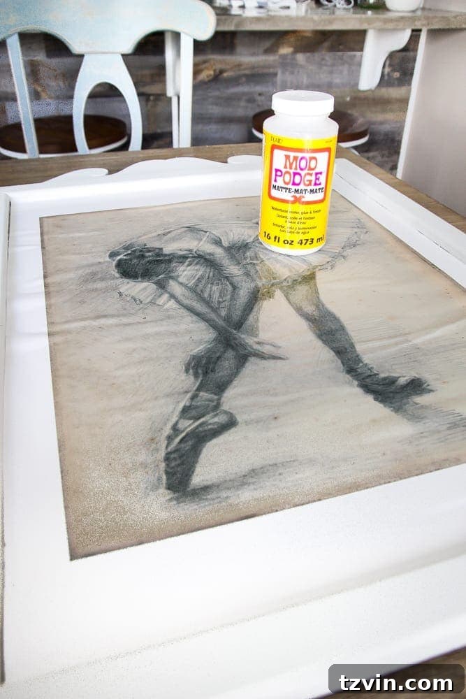 Mirror Frames Reimagined as Photo Displays 8 Step-by-step guide to adhering a ballerina art print onto a repurposed mirror surface using Mod Podge, demonstrating how to smooth out air bubbles.