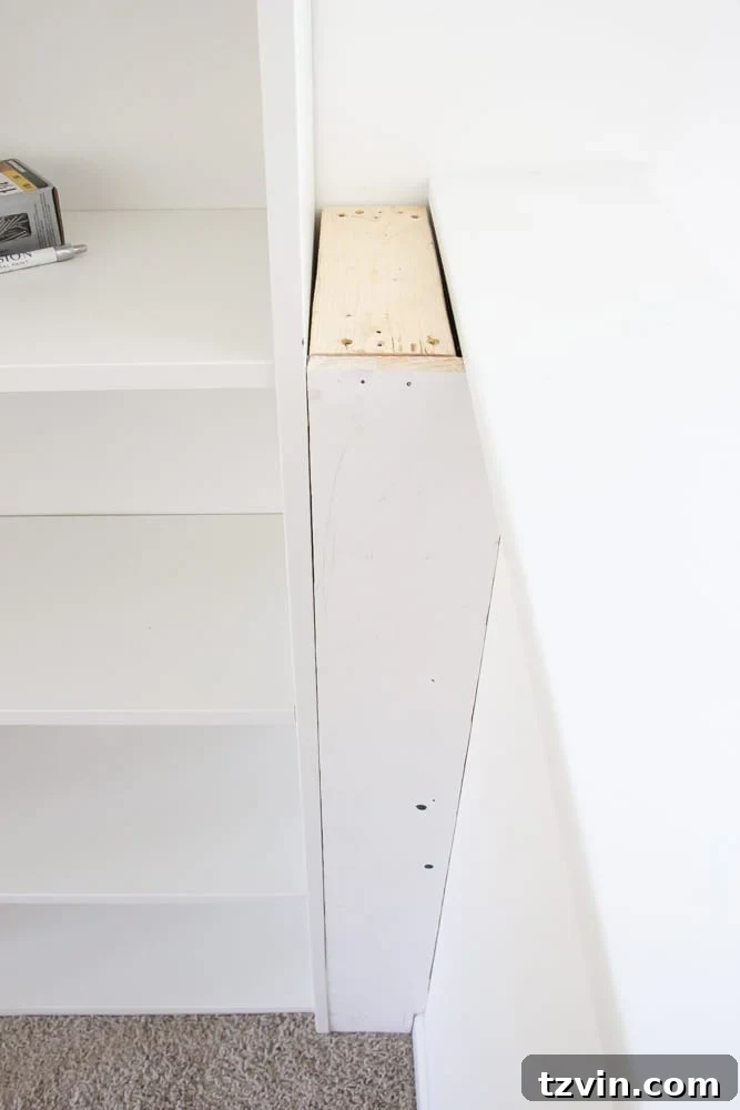 Using 1x6 boards and 2x4 boards to build a box between a bookcase and a half wall, creating a flush built-in appearance.