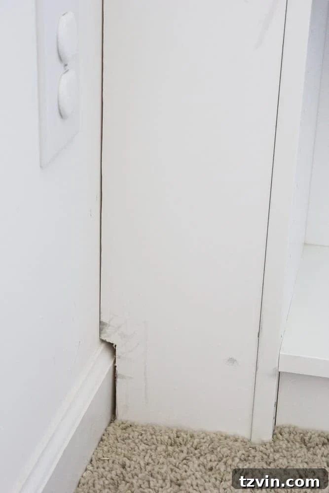 Close-up of a notched-out baseboard section on a built-in shelf, ensuring a snug fit against the wall.