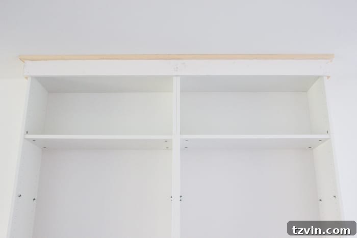 Adding a custom header with Craftsman-style molding details to IKEA bookcases for a high-end built-in appearance.