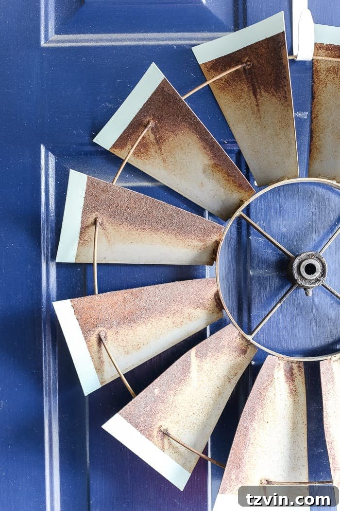 Rustic antique windmill repurposed as a unique front door wreath, showcasing creative winter decor and a love for vintage finds.