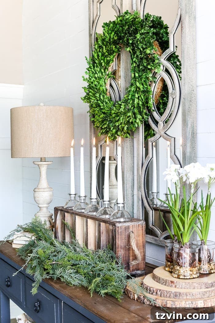 A warm and inviting winter foyer featuring a console table, decorated with a lamp, candles, greenery, and charming vintage elements, reflecting cozy home decor.