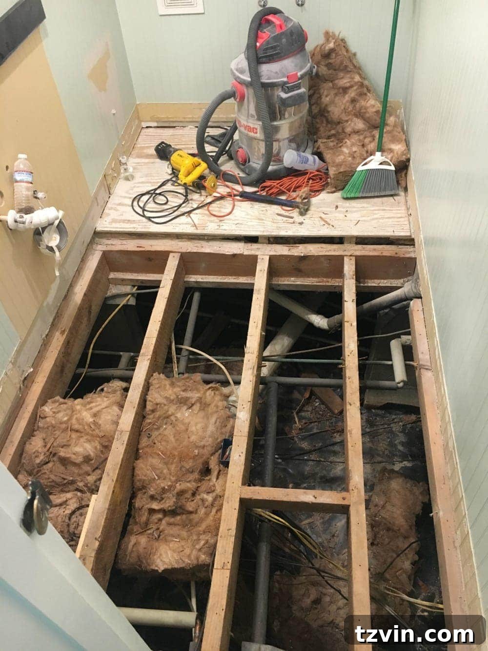 Powder Room Radiance: Faux Marble Tile Floor Upgrade 4 A large hole in the powder room floor after initial demolition, revealing the underlying structure and unexpected concrete pour from a previous renovation.