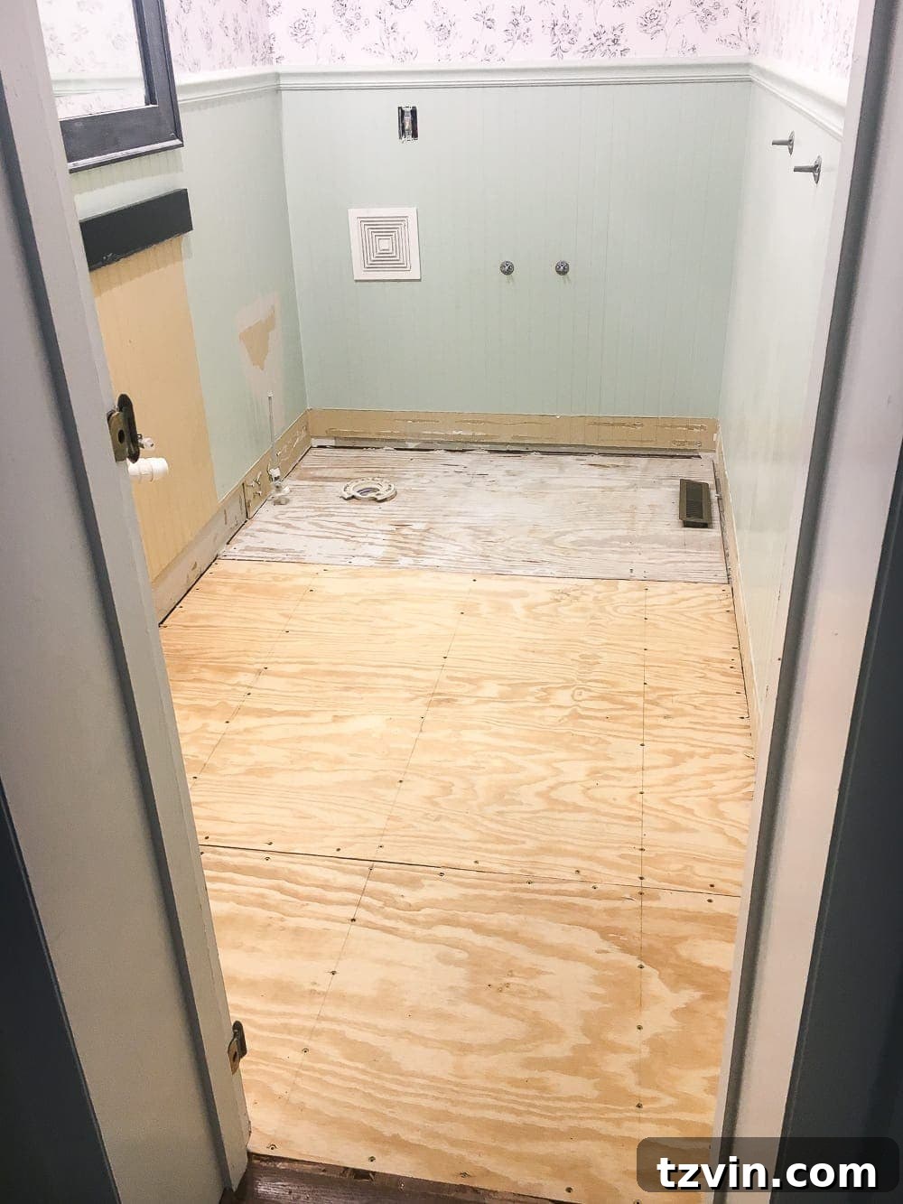 Powder Room Radiance: Faux Marble Tile Floor Upgrade 5 Contractor working on the subfloor of the powder room, addressing the uneven concrete foundation discovered beneath the old tile, a common challenge in old house renovations.