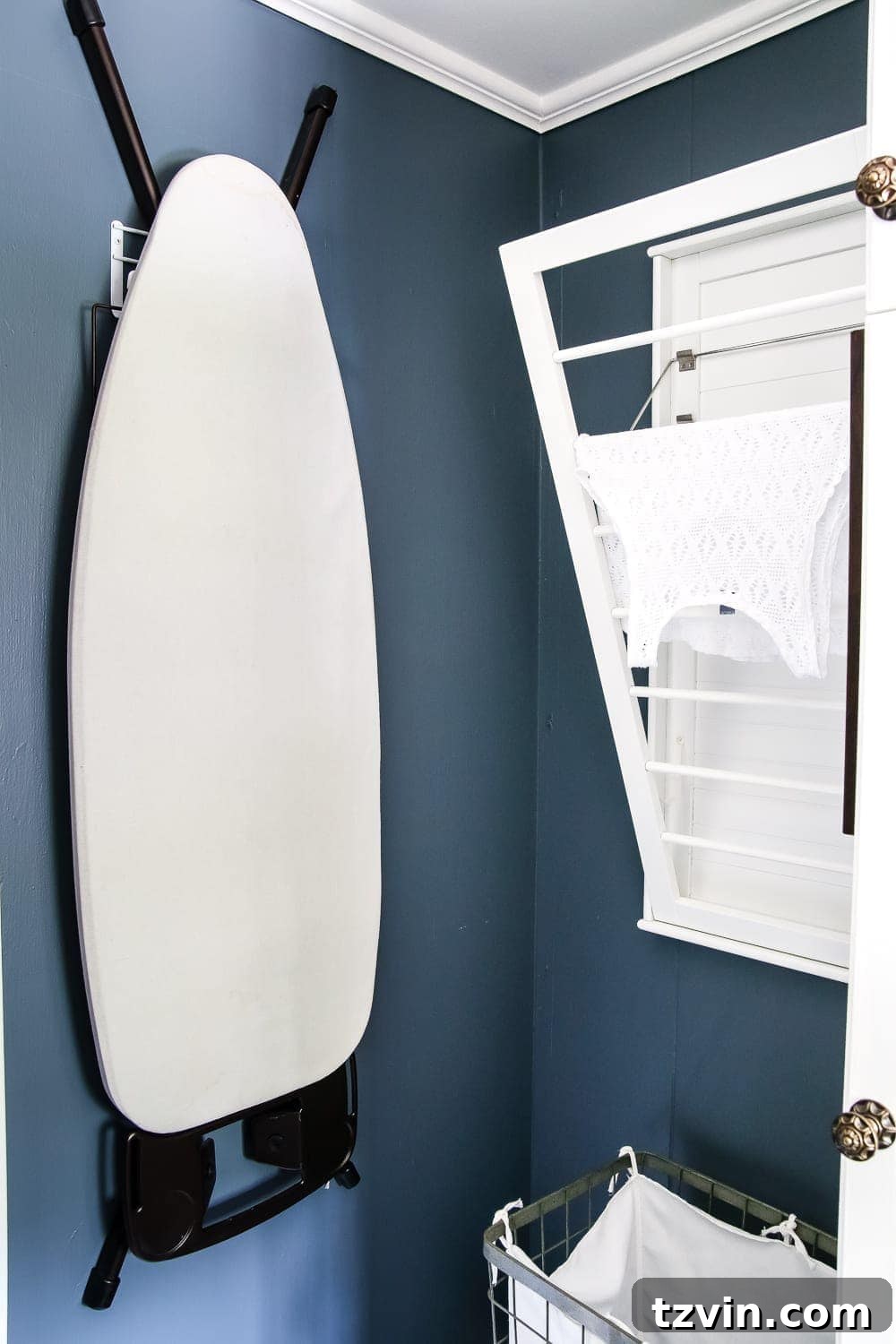 Bold Contrast Laundry Room Transformation 19 Wall-mounted drying rack and ironing board stored on a hook in a compact laundry room.