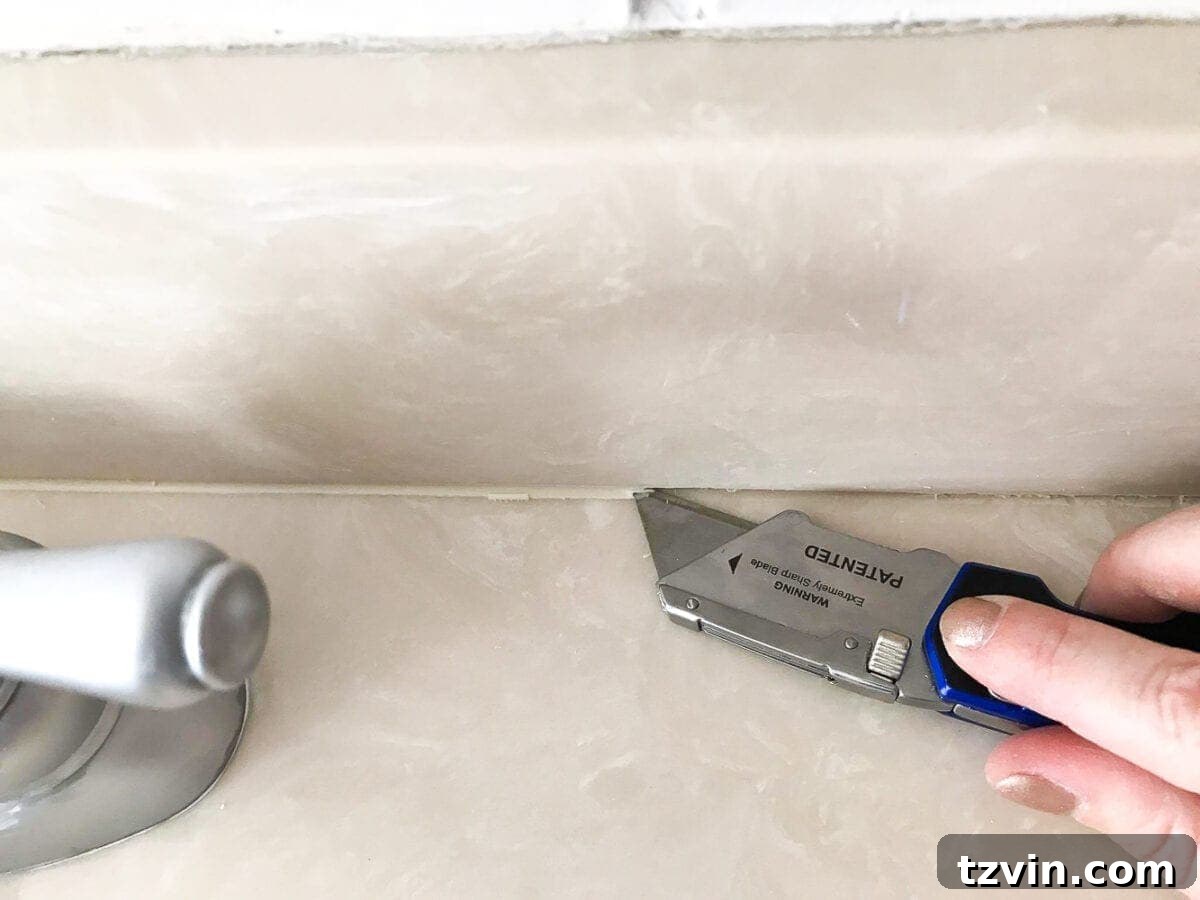 Transform Your Bathroom Counter with Paint 9 scraping away old caulk for painting a bathroom countertop
