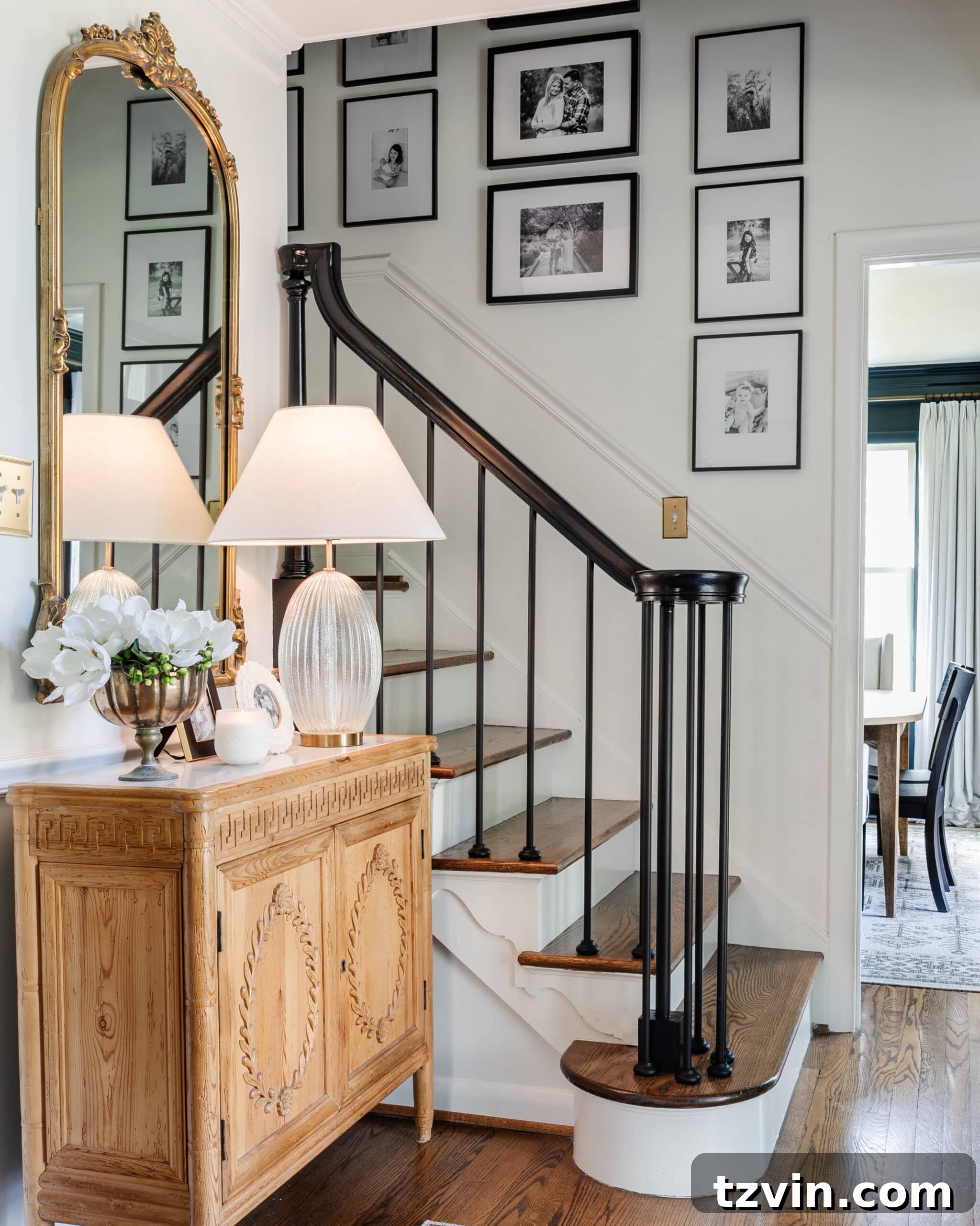 Perfect Gallery Wall Installation 7 gallery wall on stairs in an entryway with accent chest, mirror, and lamp
