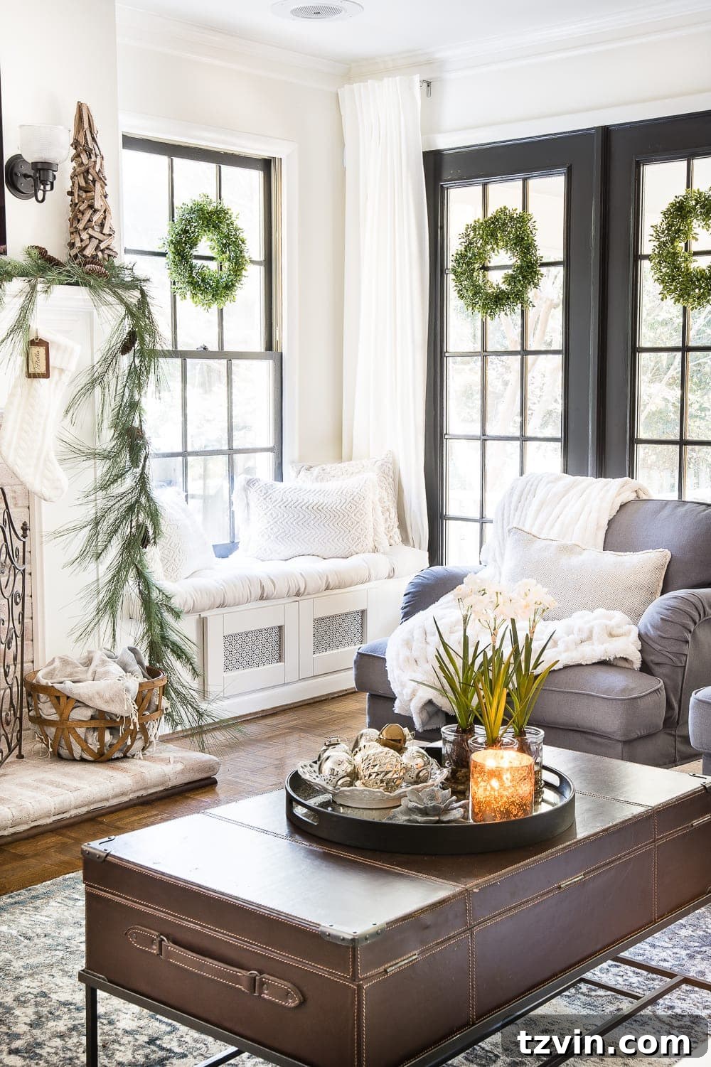 A full view of a neutral and natural Christmas living room, showcasing a fireplace, comfortable seating, and a decorated tree.