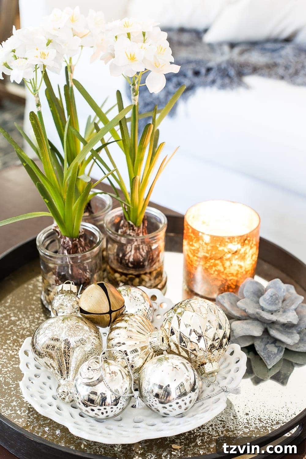 A festive Christmas tree with unique ornaments, including mercury glass and DIY crafts, standing in a neutral living room.