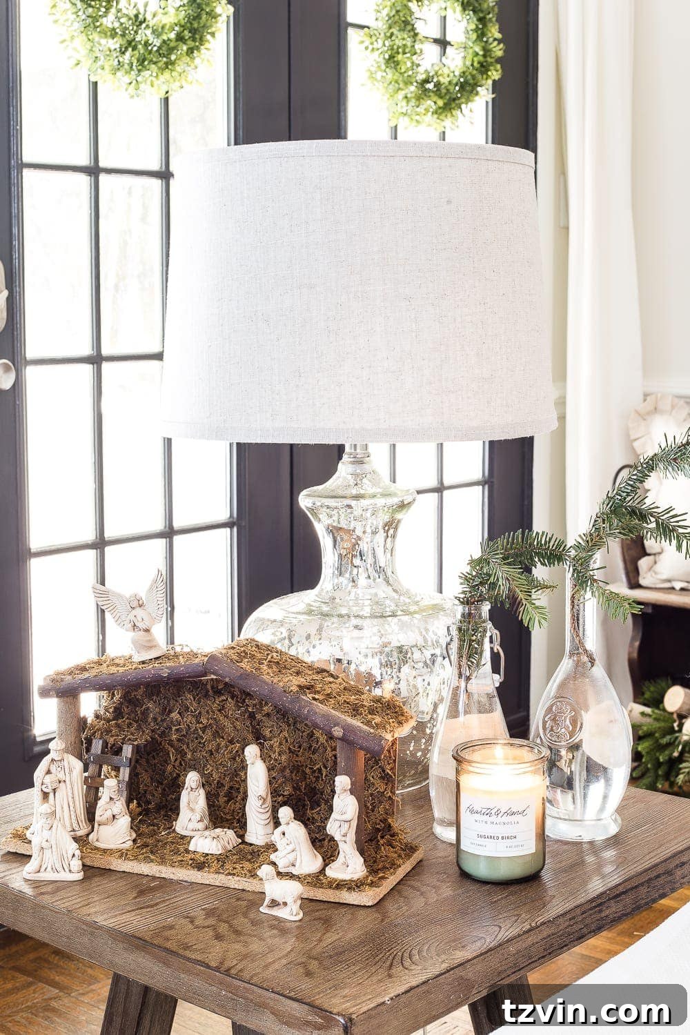 Elegant Christmas fireplace mantel with natural garland, classic stockings, and mercury glass details in a neutral home.