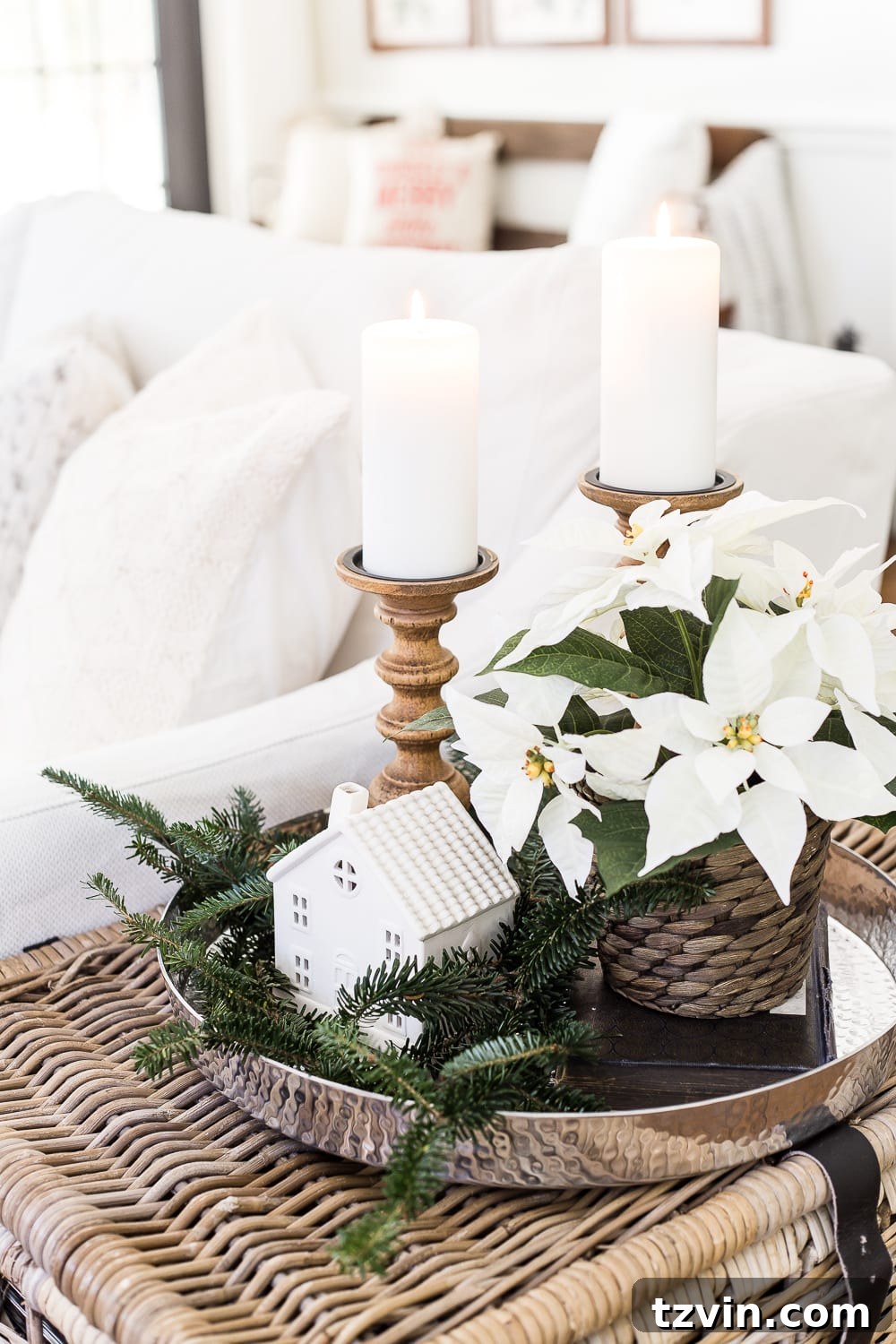 A festive corner of a neutral Christmas living room with a cozy blanket, decorative pillow, and soft holiday accents.