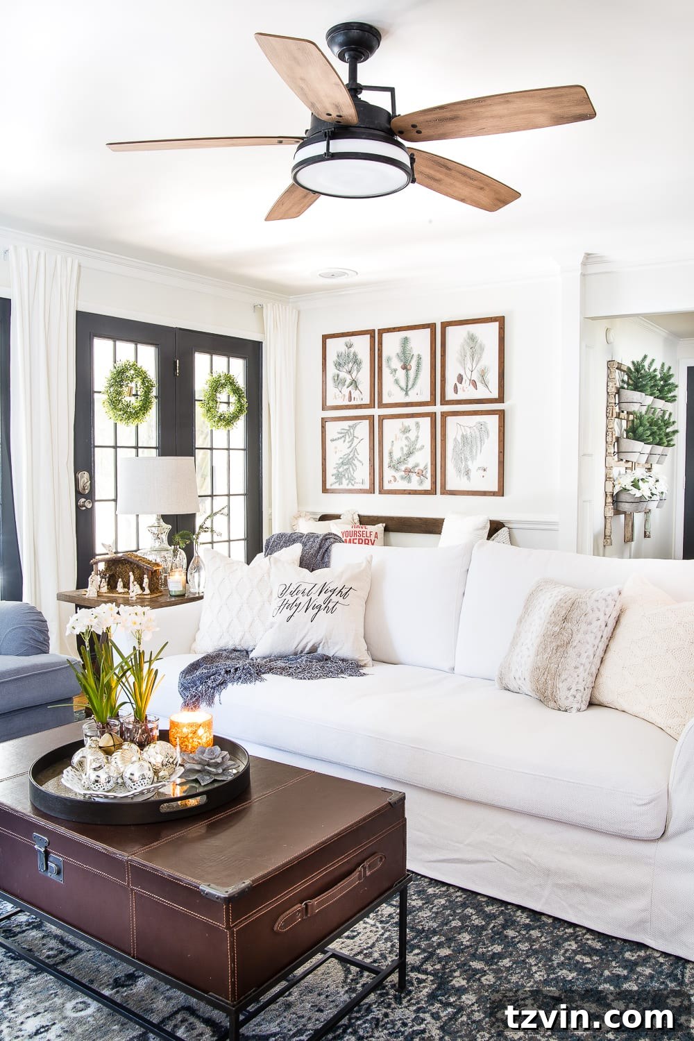 A wide view of a comfortable neutral living room decorated for Christmas, featuring a large sofa and tasteful holiday accents.