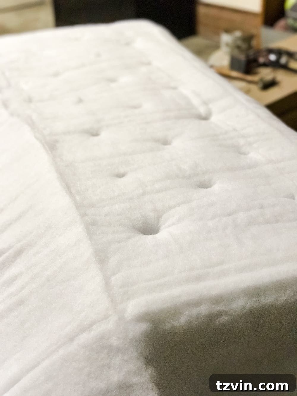 Laying batting over foam and making holes for tufts