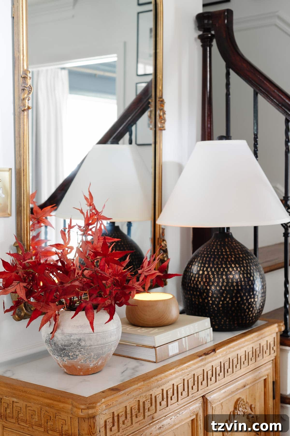 The Enduring Appeal of Classic Interior Design 3 Entry table with a classic lamp, terracotta vase of fall leaves, and a timeless wood cabinet, illustrating enduring home decor.